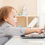 Little toddler girl  pointing to her laptop computer screen