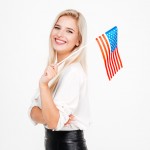 Portrait of happy young businesswoman with flag of America over white background