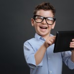 Educative gadget. Diligent clever nice boy using his tablet and looking excited while finding something interesting